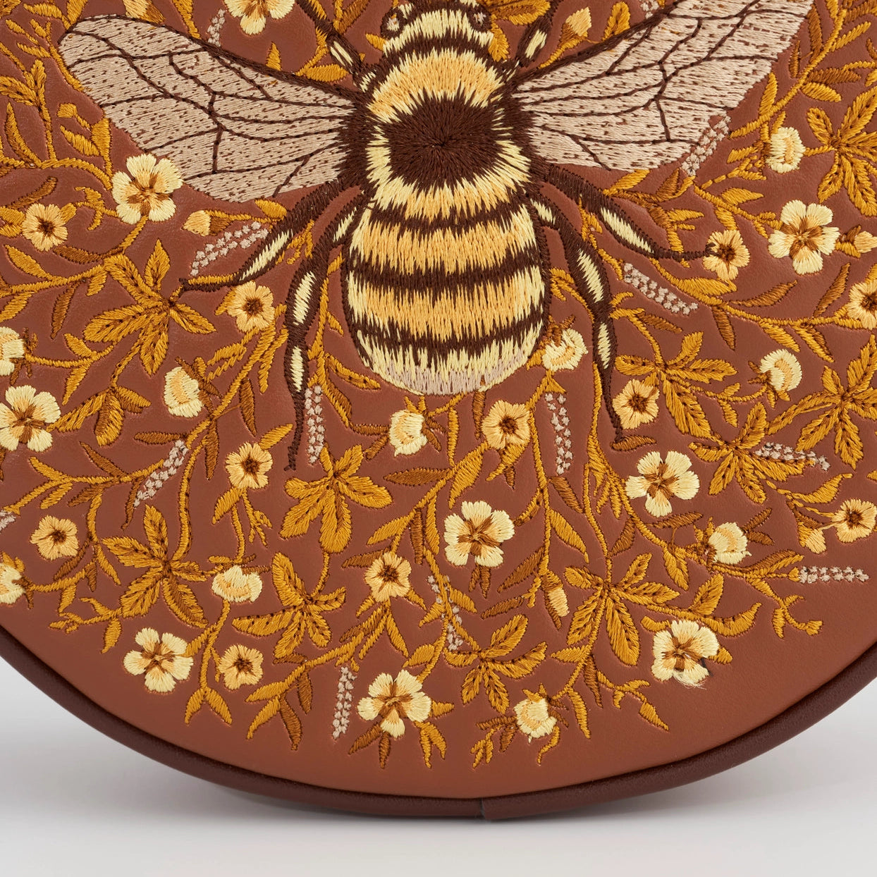Embroidered bee and floral pattern on a brown background
