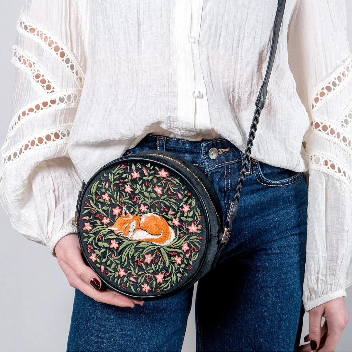Person holding a round bag with a fox design against a plain background