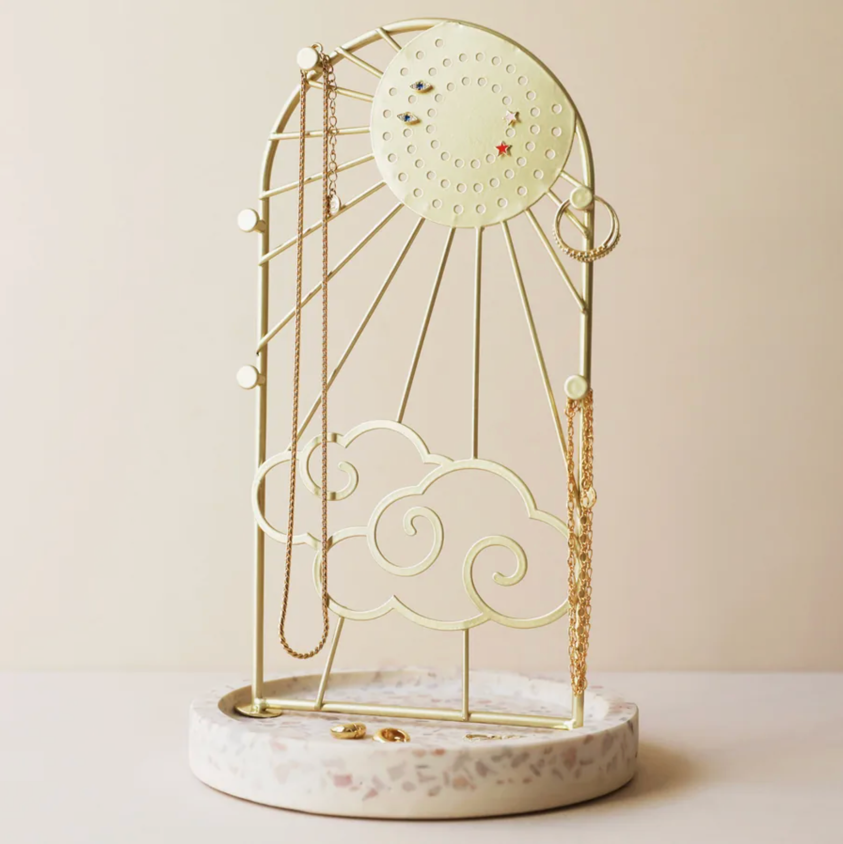 Gold sun and cloud shaped jewellery stand with a stone base.