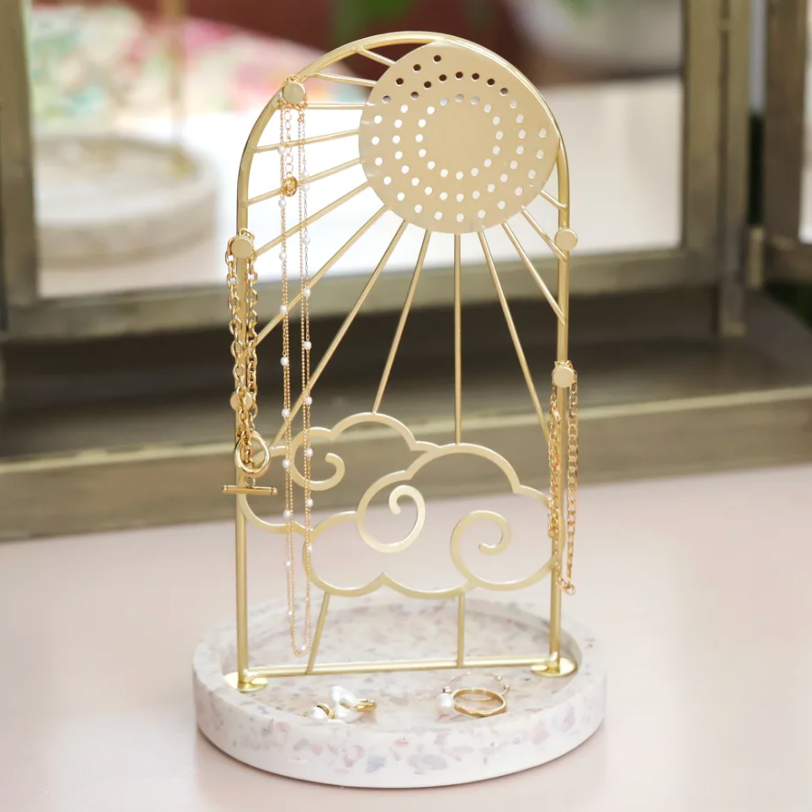 Gold sunshine and cloud jewellery stand with stone base.