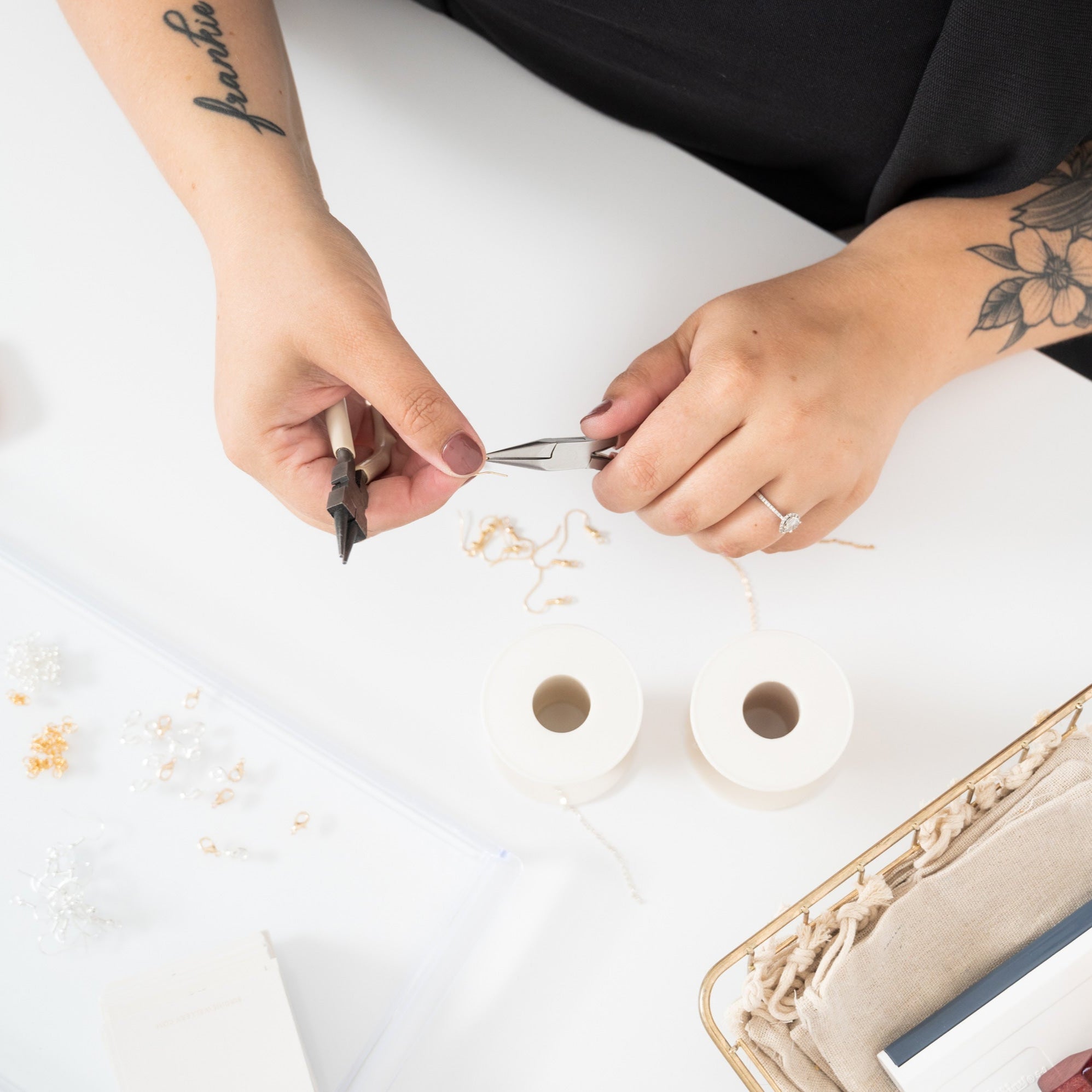 A person working on jewellry with tools and materials on a white surface
