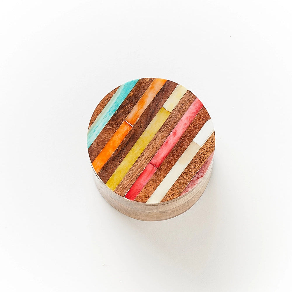 Round wooden box with multicolored striped pattern on a white background