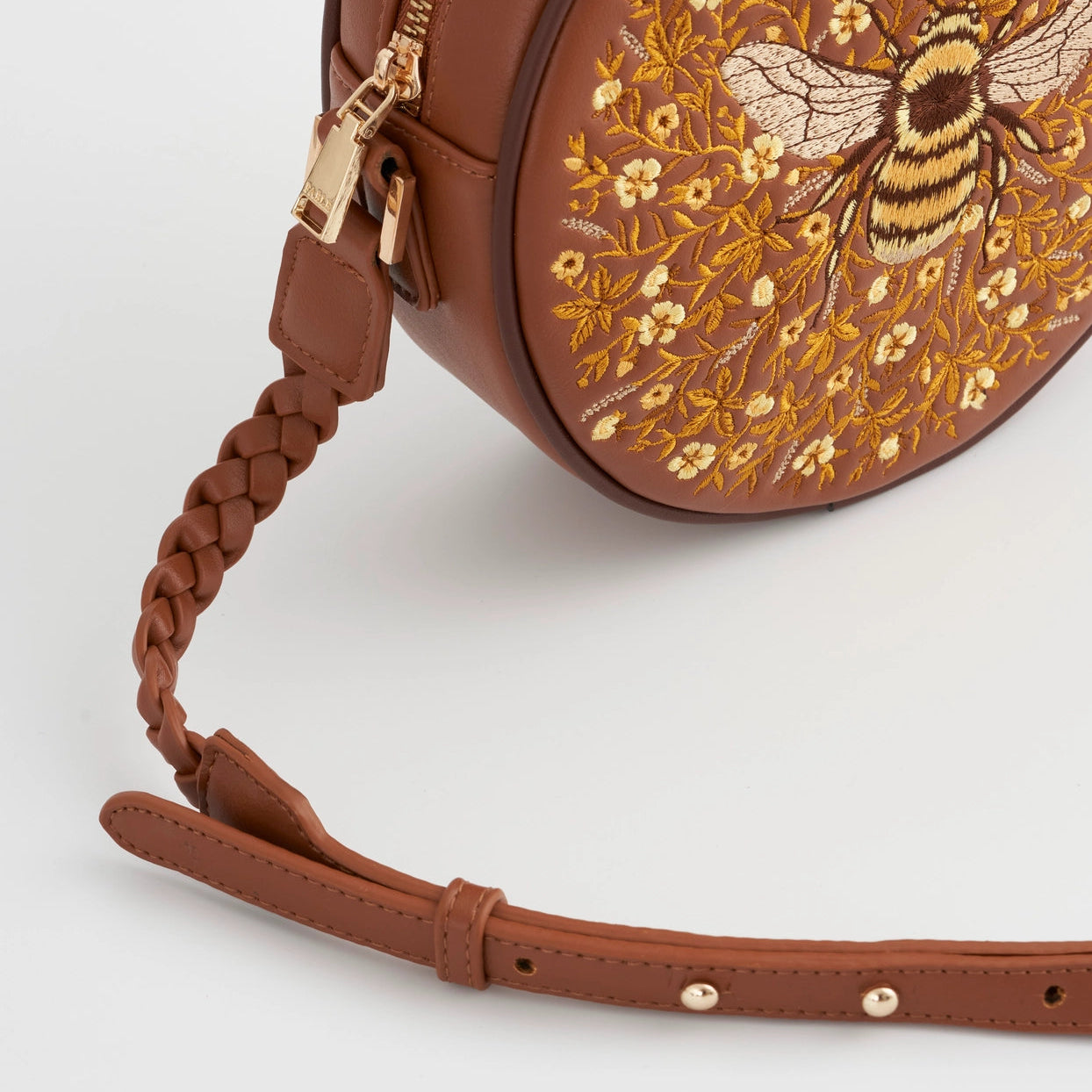 Brown round handbag with floral embroidery and a bee design on a white background